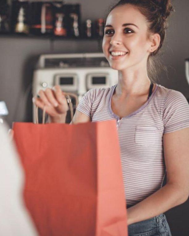 Cafe employee handing gift wrapped bag to customer